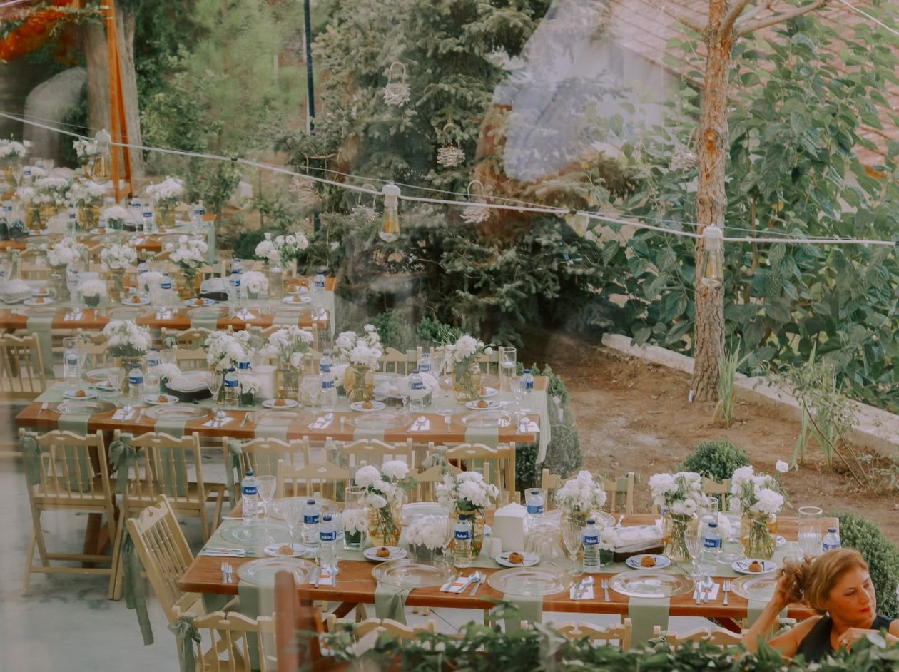 Recepción de boda al aire libre con mesas rústicas de madera y decoración floral