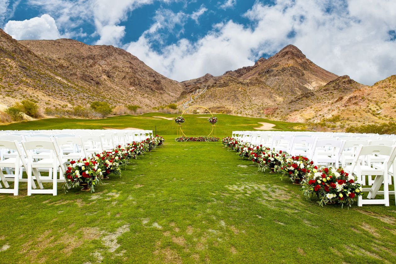Montaje de una boda al aire libre con flores y un arco frente a las montañas