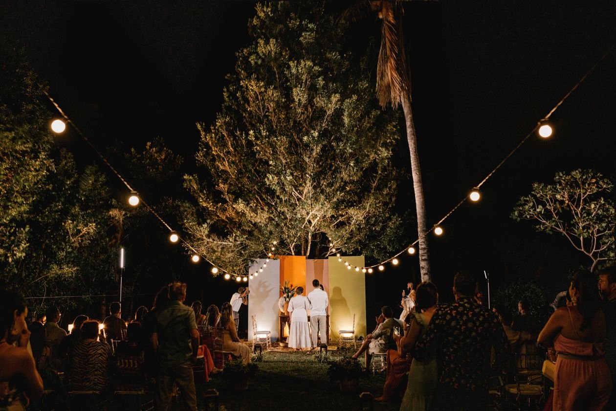 Boda nocturna al aire libre con guirnaldas de luces e invitados reunidos